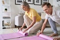 Sporty fit old couple hands rolling or unrolling yoga pilates mat at home.