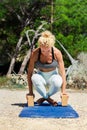 Sporty fit middle aged woman, in upward rooster pose kukkutasana on tropical beach. Female yoga instructor doing yoga Outdoor ac