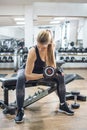 Sporty fit sportswoman lifting weights while sitting on exercise bench in gym Royalty Free Stock Photo
