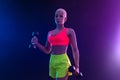 Sporty fit woman, athlete with dumbbells make fitness exercises on neon background. Download cover for music collection