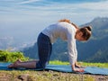 Sporty fit woman practices yoga asana Marjariasana outdoors Royalty Free Stock Photo