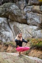 Sporty fit woman is practicing yoga on the boulder in the nature