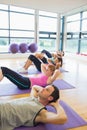 Sporty fitness class doing sit ups on exercise mats