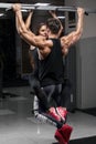 Sporty fitness couple doing pull up on horizontal bar in gym. Muscular man and woman pulling up, working out