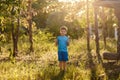 five-year-old Caucasian boy in blue t-shirt and shorts stands in the back sunlight in summer outdoors