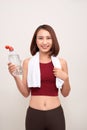 Sporty girl with bottle of water and towel on her shoulders on light background Royalty Free Stock Photo