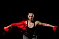 A sporty girl is doing an exercise on the cultivation of hands with dumbbells. It is bathed in red paint. Royalty Free Stock Photo