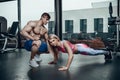 Sporty girl doing plank exercises with support of her personal trainer.