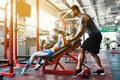 Sporty girl doing weight exercises with assistance of her personal trainer at gym. Royalty Free Stock Photo