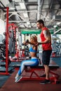 Sporty girl doing weight exercises with assistance of her personal trainer at gym. Royalty Free Stock Photo