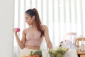 Sporty girl in fitness sport wear lifting dumbbell, fruit vegetable and healthy ingredients at kitchen. losing weight and slim. Royalty Free Stock Photo