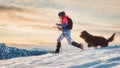 Sporty girl with her dog during an alpine trekking on the snow