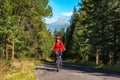 Sporty girl on mountain bike biking on road in forest with big hill at background