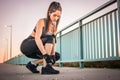 Sporty girl runner tying shoelaces on her jogging shoes while taking a break after workout outdoors Royalty Free Stock Photo