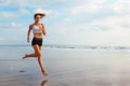 Sporty girl running by beach along sea surf Royalty Free Stock Photo