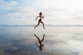 Sporty girl running by beach along sea surf Royalty Free Stock Photo