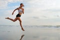 Sporty girl running by beach along sea surf Royalty Free Stock Photo