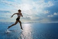 Sporty girl running by beach along sea surf Royalty Free Stock Photo