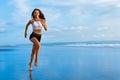 Sporty girl running by beach along sea surf Royalty Free Stock Photo