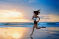 Sporty girl running by beach along sea surf Royalty Free Stock Photo