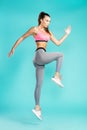 Sporty girl. Side view of young beautiful woman in sportswear jumping against blue background in studio. Sport and Royalty Free Stock Photo