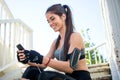 Sporty girl sitting on stairs and using mobile phone after running outdoors. Royalty Free Stock Photo