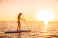 Sporty girl stand up paddle surfing with beautiful sunset or sunrise colors Royalty Free Stock Photo