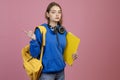 Sporty girl standing, holding yellow folder and rucksack. Royalty Free Stock Photo
