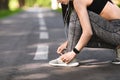 Sporty girl tying shoes laces before running, getting ready for jogging outdoors Royalty Free Stock Photo