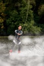 sporty girl in wetsuit rides on wakeboard in the river near forest Royalty Free Stock Photo