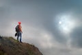 Sporty guy with a backpack on the edge of the cliff against a stormy clouds and sun. Travel concept Royalty Free Stock Photo