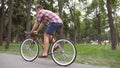 Sporty guy cycling at the park road. Young handsome man riding a vintage bicycle outdoor. Healthy active lifestyle. Side Royalty Free Stock Photo