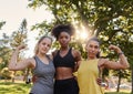 Sporty healthy young multiethnic female friends flexing their muscle looking at camera in the park - strong woman