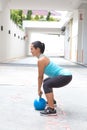 sporty hispanic woman in blue attire holding a blue kettlebell in dead lift post outdoors Royalty Free Stock Photo