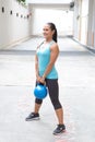 Sporty hispanic woman in blue lifting blue kettlebell for dead lift, outdoors Royalty Free Stock Photo