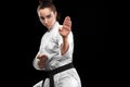 Sporty karate and taekwondo woman in white kimono with black belt on dark background. Sport concept with copy space. Royalty Free Stock Photo