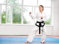 Sporty karate and taekwondo woman in white kimono with black belt.