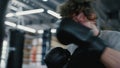 Sporty kickboxer training alone at gym. Sportsman making blows in sport club