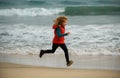 Sporty kid running in nature. Little boy child running along ocean. Kid runs on sand beach. Royalty Free Stock Photo