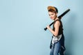 Sporty little boy in sleeveless shirt, jeans and cap preparing to hit with baseball bat from his shoulder. Royalty Free Stock Photo