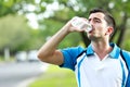 sporty male runner drinking mineral water at the break after run