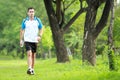 Sporty male runner walking by at roadside while take a breath