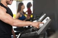 Sporty man adjusting speed on treadmill in gym