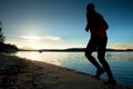 Sporty Man doing Morning Jogging on Sea Beach at Bright Sunrise Silhouettes Royalty Free Stock Photo