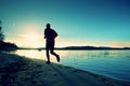 Sporty Man doing Morning Jogging on Sea Beach at Bright Sunrise Silhouettes Royalty Free Stock Photo