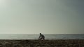 Sporty man doing warm-up squatting on sand. Karate fighter stretching on beach. Royalty Free Stock Photo