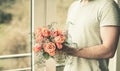 Sporty man holding a festive orange bouquet in his hands against the background of a window and a natural background