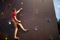 Sporty man practicing rock climbing in gym on artificial rock training wall outdoors. Young talanted slim climber guy on Royalty Free Stock Photo