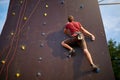 Sporty man practicing rock climbing in gym on artificial rock training wall outdoors. Young talanted slim climber guy on Royalty Free Stock Photo