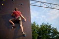 Sporty man practicing rock climbing in gym on artificial rock training wall outdoors. Young talanted slim climber guy on Royalty Free Stock Photo